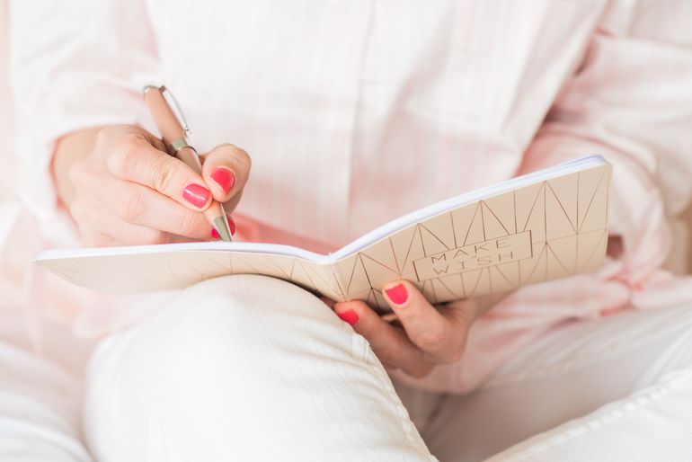 Femme écrivant sur son carnet rose