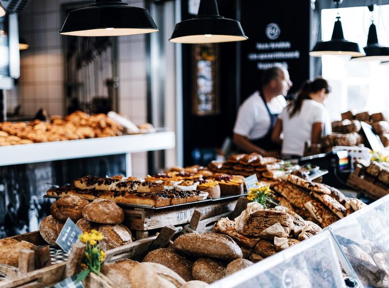 L'étal intérieur d'une patisserie-boulangerie avec deux employés au fond un peu floutés