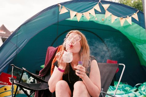 Jeune fille devant une tente qui souffle des bulles de savon